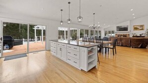 A spacious kitchen with a large island, white cabinetry, and pendant lighting. - Luxury 5b 3ba on 10 acres w Lake view, Firepit, Hot Tub, Gameroom, close to Ski! (Sanbornton)