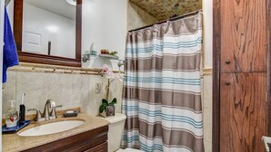 Une salle de bain équipée d’un lavabo, d’un miroir, de toilettes et d’un rideau de douche à rayures.