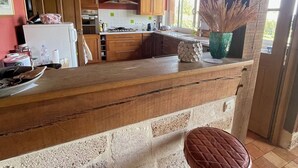 Une cuisine rustique avec des poutres en bois, un comptoir en pierre et deux tabourets.
