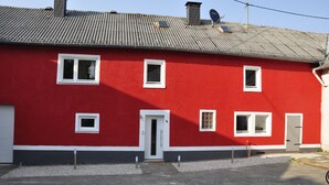 A red building with a tiled roof, multiple windows, and a door.