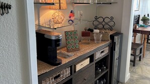 A kitchen with shelves holding glassware, a coffee maker, and decorative items.