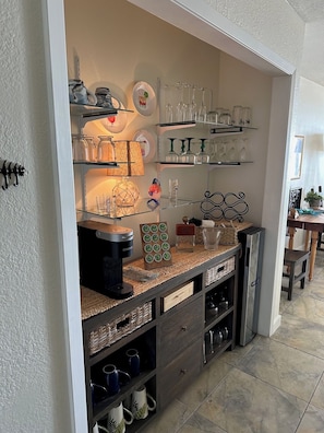 Una cucina con scaffali che espongono bicchieri, una macchina per il caffè e oggetti decorativi.