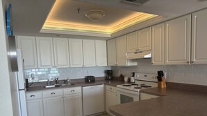 A kitchen with white cabinets, a dishwasher, a stove, and a coffee maker.