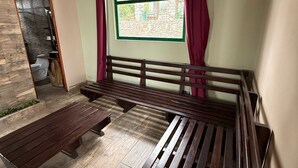 Una habitación con un banco de madera, un ventanal de marco verde y vistas al exterior.