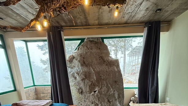 Una habitación con dos camas, un llamativo elemento rocoso y vistas a través de una ventana.