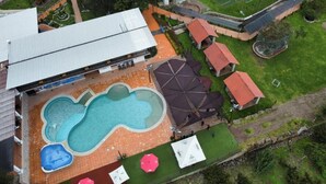 Vista aérea de una propiedad con piscina, cancha de tenis y zona de patio cubierta.