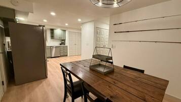 Une cuisine moderne avec une table à manger en bois, des chaises et un luminaire suspendu.
