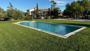 Ein rechteckiger Pool mit glasklarer, blauer Wasseroberfläche, umgeben von gepflegtem Grün.