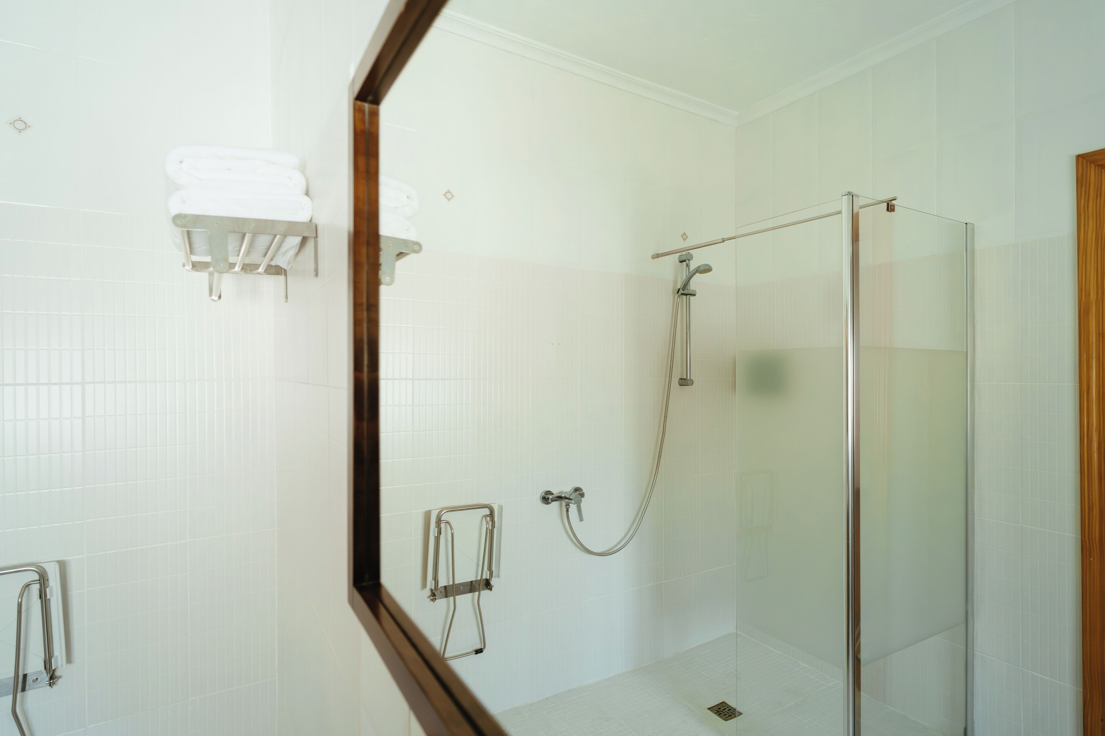 Ein modernes Badezimmer mit einer Duschkabine aus Glas, einem Handtuchhalter und einer Haltestange.