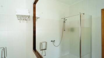 Ein modernes Badezimmer mit einer Duschkabine aus Glas, einem Handtuchhalter und einer Haltestange.