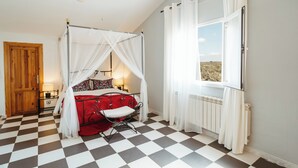 Ein Schlafzimmer mit einem Himmelbett, einem Schachbrettmuster-Boden, einem Fenster mit Vorhängen und einer Holztür.
