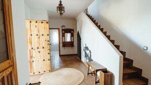Eine Treppe führt zu einer zweiten Etage, eine Holztür mit Sterndekoration, ein runder Teppich und eine kleine Holzbank.