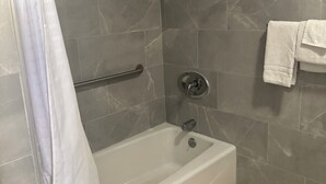 A bathroom with a bathtub, shower, and a towel rack. - All 8 Motel (Azusa)