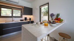 A modern kitchen with a marble countertop, a built-in oven, and a large window. - Morea Club West House with Private Heated Pool (Kalamat)