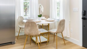 A dining area with a round table, four chairs, and a potted orchid.