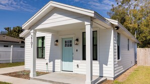 A single-story house with a front porch, a light blue door, and a small front yard.