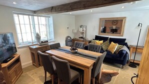 A spacious living area with a wooden dining table, comfortable seating, a fireplace, and a television.