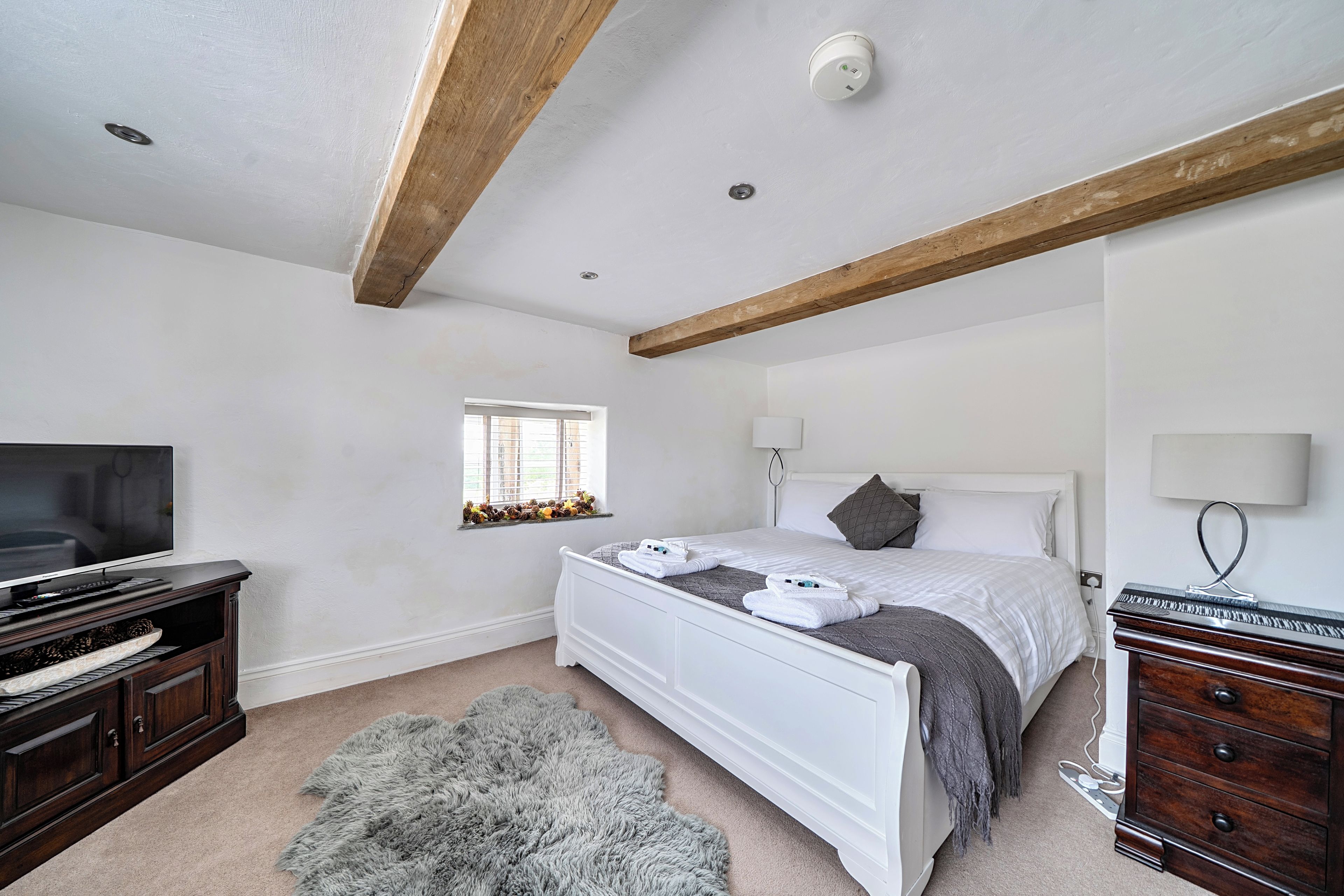 A bedroom with a bed, a television, a dresser, and a window.