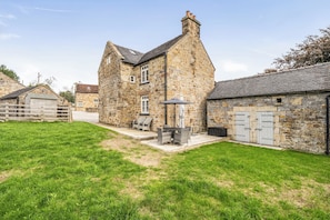 A stone building with a large patio area, outdoor seating, and a grassy lawn. - Stunning Cosy Rustic Farmhouse Alton Towers Peaks (Leek)