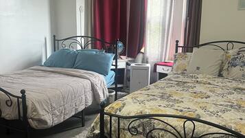 Une chambre avec deux lits simples, un bureau et un radiateur.
