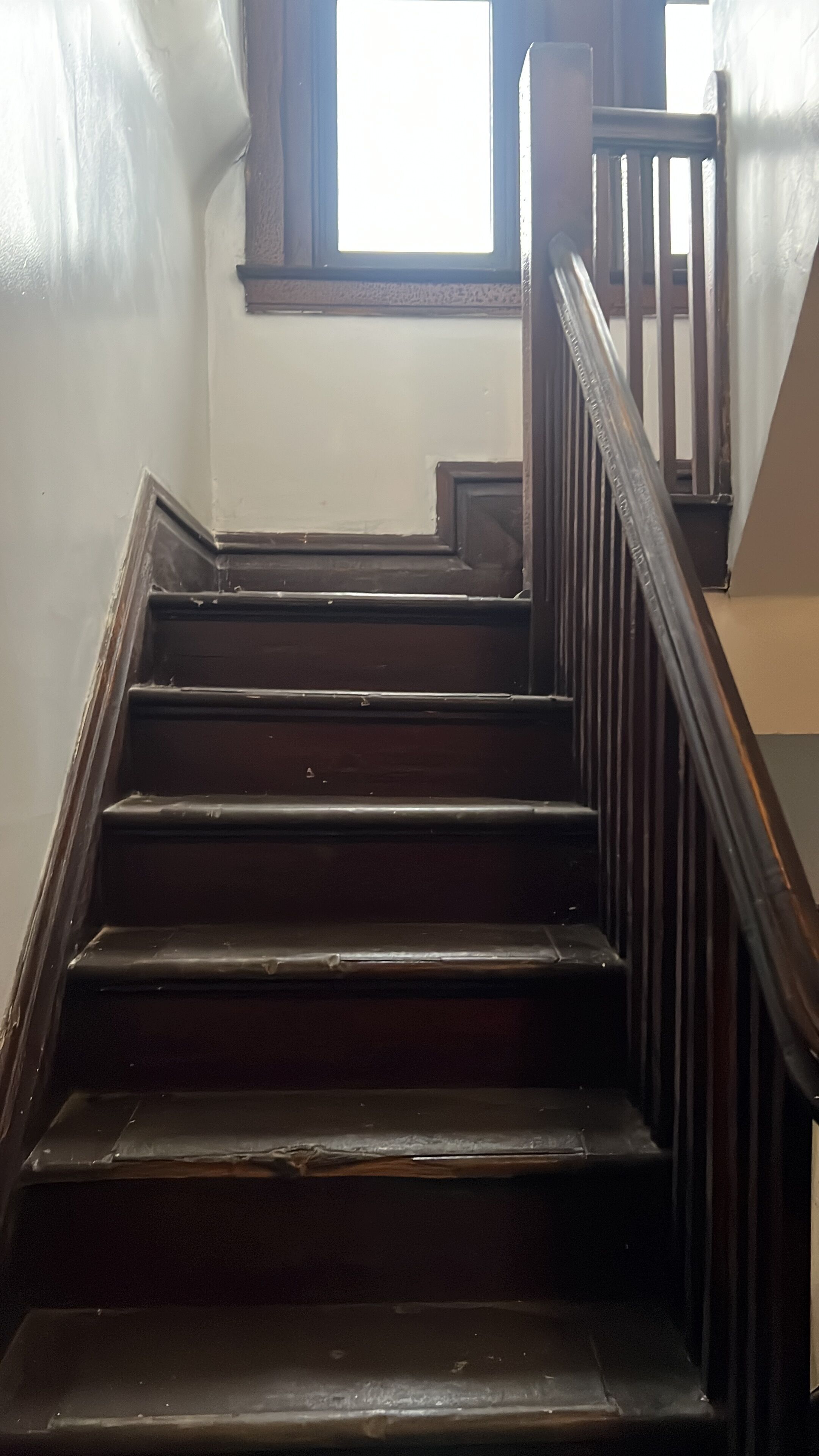 A wooden staircase with a handrail, leading to an upper floor.