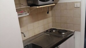 Een kleine keuken met een magnetron, twee spoelbakken en een fornuis.