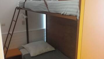 A bunk bed room with a ladder, a small bedside table, and a single bed.