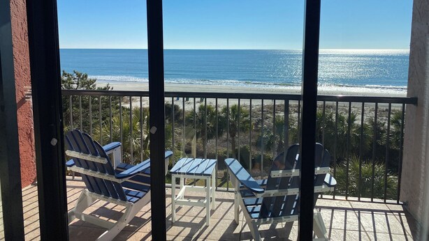 Un balcon avec vue sur la plage et l’océan.