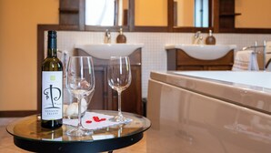 A wine bottle and two glasses on a tray in a hotel bathroom.