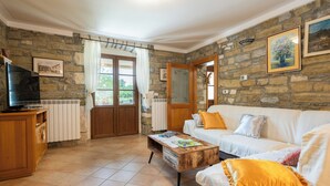 A living room with a stone wall, a wooden cabinet, a television, a white sofa, and a coffee table.