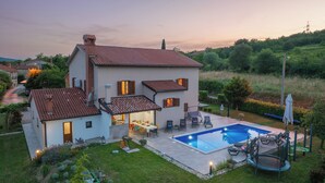 A two-story house with a swimming pool, outdoor seating, and a well-maintained garden.