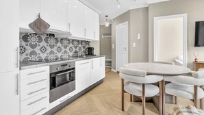 A modern kitchen with white cabinets, a patterned backsplash, and a round dining table with chairs.