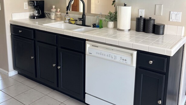 A modern kitchen with dark cabinets, a white countertop, and a built-in dishwasher. - Beautiful 3-bedroom 2-baths with a pool and RV parking. (Bakersfield)
