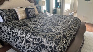 A bedroom with a large bed, a wooden headboard, and a nightstand with a lamp. - Beautiful 3-bedroom 2-baths with a pool and RV parking. (Bakersfield)