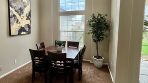 A dining area with a table, chairs, a ceiling fan, a large window, and a potted plant. - Beautiful 3-bedroom 2-baths with a pool and RV parking. (Bakersfield)