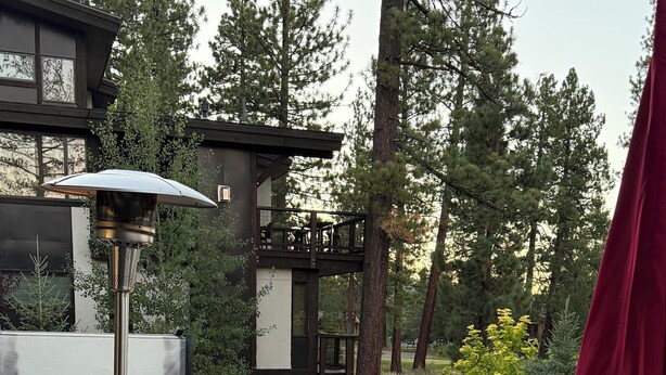 Un patio exterior con una chimenea de piedra, sillones de descanso y una mesa redonda.