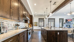 Una cocina moderna con armarios de madera oscura, una isla grande e iluminación colgante.