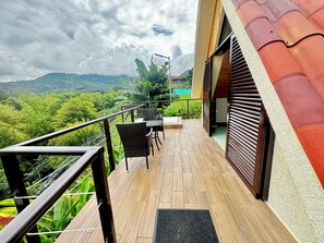 Un balcon avec un plancher en bois, des chaises en osier et une table.