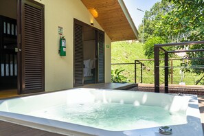 Un espace de bien-être avec un jacuzzi, des volets en bois et une vue sur la verdure.