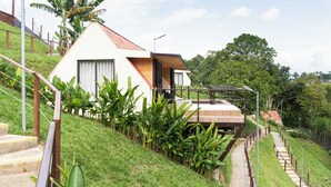 A modern house with a sloped roof, a wooden deck, and a staircase leading to a wooden door. - Pachakuti Ecovida Hotel (Caicedonia)