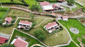 A residential area with multiple houses, each with a red-tiled roof, surrounded by well-maintained lawns and gardens. - Pachakuti Ecovida Hotel (Caicedonia)