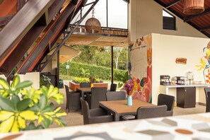 Un espace extérieur aménagé pour les repas, avec des meubles en osier, un coin café et une vue sur le jardin.