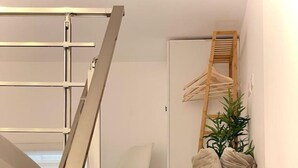 A staircase with wooden steps and a metal handrail, leading to a room with a white door and a plant.