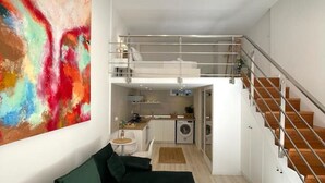 A modern apartment with a living room, a kitchen, and a staircase.