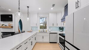 Una cocina moderna con armarios blancos, una isla grande, lavavajillas y horno empotrado.