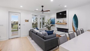 Una sala de estar moderna con un sofá seccional gris, un televisor de pantalla plana y una decoración con una tabla de surf.