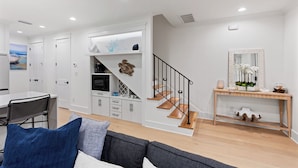 Una sala de estar moderna con una escalera, paredes blancas y un comedor.