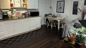 A kitchen with white cabinets, a microwave, and a dining area with a table and chairs.