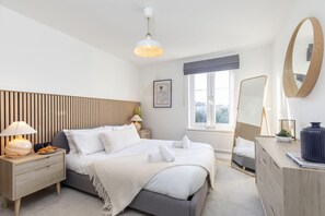 Een moderne slaapkamer met een bed, nachtkastjes, een kaptafel, een spiegel en een raam met uitzicht.