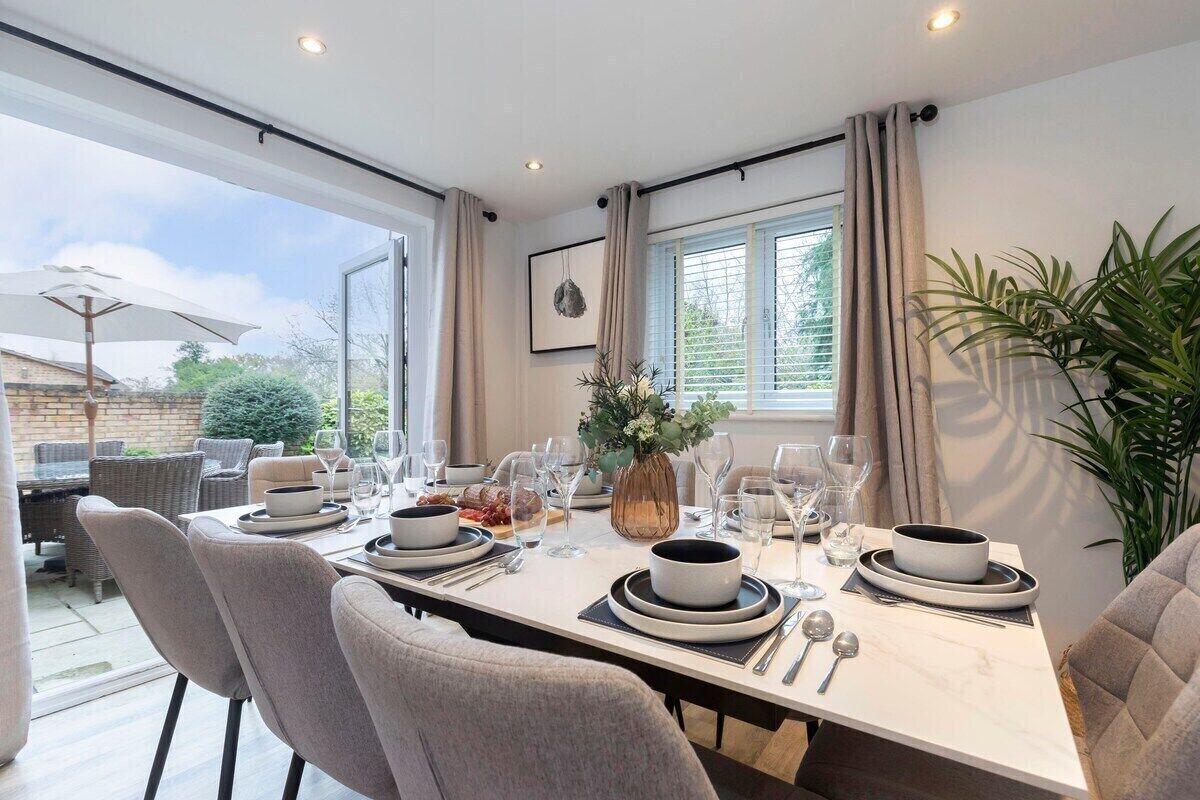 A dining area with a table set for four, surrounded by chairs, with a view of the outdoors.